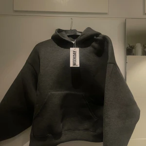 Mörkgrå hoodie från Weekday, stl S - Säljer en mörkgrå hoodie från Weekday i storlek S. Hoodien har en klassisk känguruficka framtill, huva och en loose passform. Perfekt för lager-på-lager och chill dagar. Materialet är mjukt och skönt, troligtvis bomullsmix.