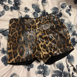 Leopardmönstrade paljettshorts - Snygga shorts med leopardmönster och glittrande paljetter över hela tyget. De har en tight passform och elastisk midja för extra komfort. Perfekta för dig som vill sticka ut och älskar djurmönster och bling.