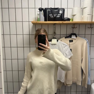 Beige ribbstickad tröja med vida ärmar - Säljer en beige ribbstickad tröja med snyggt avslappnad passform och vida ärmar. Tröjan har en högre rund halsringning och är perfekt för lager-på-lager. Enkel att styla till både jeans och kjol.