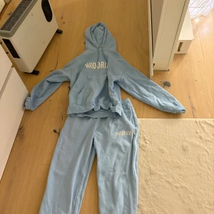 Ljusblå hoodie från Hoodrich - Säljer en ljusblå hoodie från Hoodrich med vit logga på bröstet. Hoodien har huva och ribbade muddar vid ärmslut och nederkant. Perfekt för en avslappnad och trendig stil. Materialet känns mjukt och bekvämt, perfekt för chill dagar. Xs-S