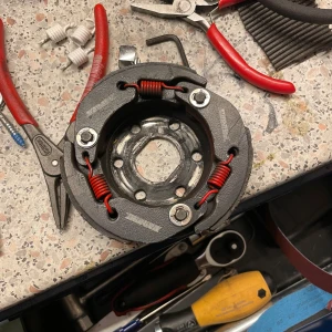 Scooter Koppling - Malossi koppling för scooter/moped, robust konstruktion med röda förstärkta fjädrar. Passar flera modeller, perfekt för trimning eller utbyte. Lätt begagnat skick, mindre spår av användning men fullt fungerande.