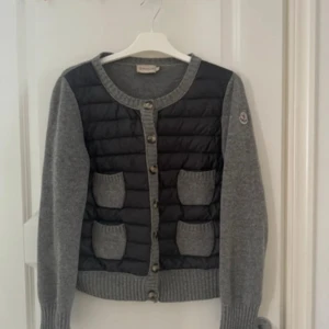 moncler cardigan  - intressekol på min snygga cardigan från Moncler i grått fyra fickor och knappar hela vägen. Ärmar och rygg är stickade i grått, medan framsidan är svart och vadderad. Perfekt för lager-på-lager under kyliga dagar. storlek L men sitter som en S 