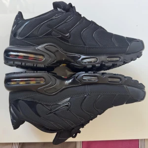 Nike Air Max svarta sneakers - Svarta Nike Air Max sneakers med snygga vågformade detaljer och synlig Air-dämpning i sulan. Skorna har mesh och syntetmaterial, diskret Nike-logga på sidan och snörning framtill. Perfekta för dig som gillar en clean och sportig look.