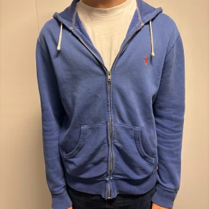 Blå Ralph Lauren zip hoodie - Blå Ralph Lauren zip hoodie✅ Skick 6/10✅ Lite små slitningar på olika ställen✅ Storlek S men passar även M✅
