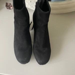 Svarta mockaboots från H&M, storlek 36 - Säljer ett par svarta boots i mockaimitation från H&M med chunky klack och rund tå. Skorna har dragkedja på insidan för enkel påtagning och en stilren, minimalistisk look som passar till många outfits.