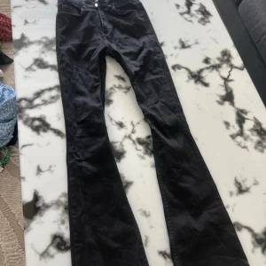 Svarta bootcut jeans - Snygga svarta jeans med bootcut-modell och klassisk femficksdesign. Jeansen har en smal passform upptill och utsvängda ben, vilket ger en retro och trendig look. Perfekta för dig som vill ha en stilren och cool vibe.