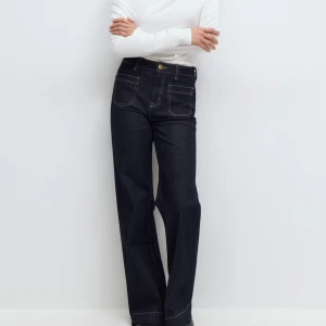 Mörkblå wide jeans med hög midja - Snygga mörkblå jeans med breda ben och hög midja. Jeansen har framfickor med tydliga kontrastsömmar och klassisk knappstängning. Perfekta för dig som gillar en avslappnad och trendig look. Helt nya med prislapp kvar har dock inget kvitto hittar inte det Darför kan ja inte lämna tbx 