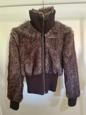 Brun pälsjacka  - Supersnygg brun pälsjacka från Clockhouse. Jackan har hög krage, dragkedja framtill och har muddar. Står ingen storlek men skulle säga s/xs.