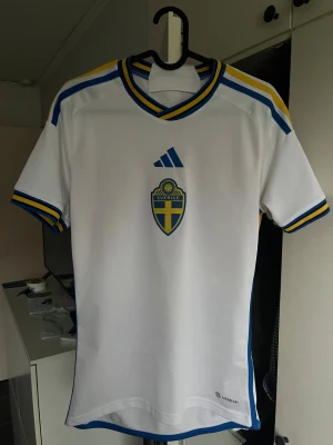 Sverige fotbollströja - Jag säljer en vit Sverige fotbollströja från Adidas med blå och gula detaljer. Jag säljer dem för att den inte passar mig längre. Den är i mycket bra skick 8/10. Jag har bara använt den nån gång innan de blev för liten.