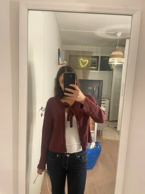 Vinröd kofta med knyt framtill - Säljer en vinröd kofta med knyt framtill från lager 157. Koftan har en croppad passform och långa ärmar, perfekt att slänga över ett linne eller t-shirt. Materialet känns mjukt och lätt, och färgen är djup vinröd som ger en chill vibe. Passar dig som gillar enkla men snygga detaljer.