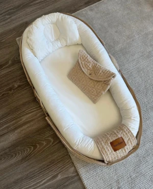 Bärbar babynest  -  – 100% ekologisk bomull – Babynest kanter är fyllda med fiber – Tvättbar både in- & utvändigt, 30 grader – Medföljer en mindre skötväska samt babykudde. – Kan användas från födseln till ca 2 års ålder. – Produkten är Oeko-Tex Standard 100 certifierad vilket säkerställer att den är fri från skadliga kemikalier. Innermått: L:75cm x B:33cm x H:12cm Yttermått: L:93cm x B:48cm x H:12cm Fotdelen kan öppnas och förlängas upp till 93 cm 