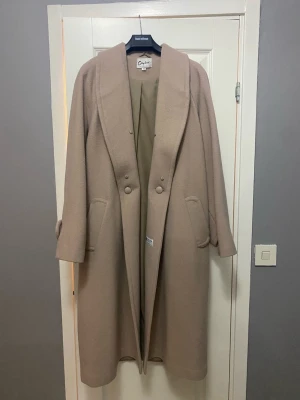 Kappa från H&M - Elegant kappa Citylook, designad av H&M. Den har en klassisk krage och knäppning framtill med stora knappar. Kappan har praktiska fickor och en stilren design.