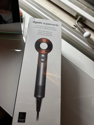 Dyson Supersonic hair dryer (oöppnad) - Dyson Supersonic hårfön med fem stylingtillbehör: styling concentrator, smoothing nozzle, diffuser, gentle air attachment och flyaway attachment. Designad för snabb torkning utan extrem värme och passar olika hårtyper.
