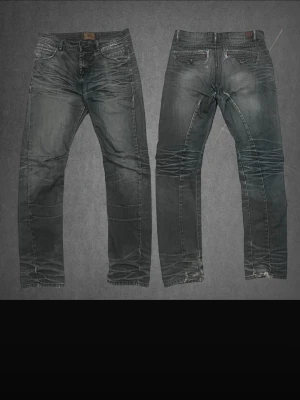 Selvedge jeans - Säljer ett par väldigt unika vintage selvedge mörkblå/grå jeans från 1953 Denim Brand by KappAhl med snygga slitningar och röda sömmar. Modellen är tapered med klassisk femficksdesign. Perfekt passform för dig som gillar stilrena jeans med lite edge och unika slitningar.