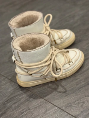 Vita moon boots från Inuikii -  Säljer ett par snygga vita boots från Inuikii i mycket bra skick. De har en cool snörning och är perfekta för vintern. Skorna är gjorda i vitt skinn och har en mysig insida som håller fötterna varma.