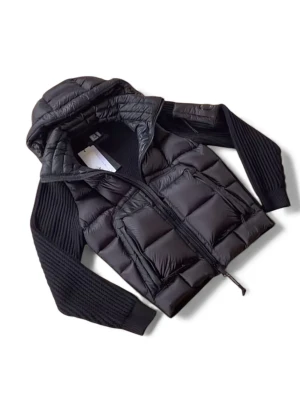 C.P. Company cardigan jacket  - Säljer en svart pufferjacka från C.P. Company med stickade ärmar och huva. Jackan har två stora fickor framtill, dragkedja och en ikonisk linsdetalj på ärmen. Materialet är en mix av polyester och stickad textil, perfekt för kyliga dagar.