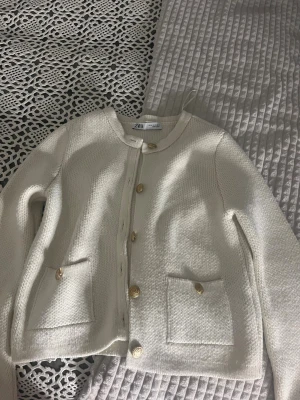 Vit stickad kofta från Zara med guldknappar - Snygg vit stickad kofta från Zara i storlek M. Koftan har rund hals, långa ärmar.  Den passar även dig som har xs/s!!💕💕