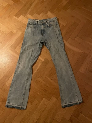 Ljusblå flared jeans från Zara - Säljer ett par ljusblå jeans från Zara med flared passform med utsvängda ben och klassisk femficksdesign. Jeansen har normal midja och är tillverkade i bomull. Snyggt slitna detaljer vid benslut och en avslappnad vibe. Perfekta för dig som gillar en enkel och clean look.