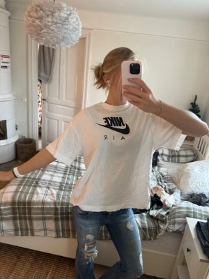 Vit Nike Air t-shirt i bomull - Säljer en vit Nike Air t-shirt i bomull med svart logga framtill. Oversized fit och klassisk rund hals. Perfekt för en chill och sportig look. T-shirten har korta ärmar och är riktigt skön att bära.