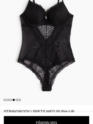 Svart spetsbody med push-up - Säljer en svart body med push-up och tunna axelband. Bodyn har genomskinliga meshpartier och detaljer i blommig spets som ger en snygg look. Perfekt för dig som gillar stilrena och feminina underkläder.