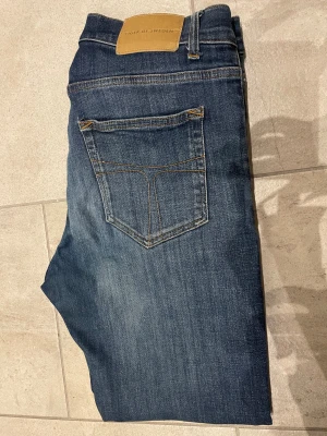 Tiger of Sweden blå jeans 32/34 - Säljer ett par klassiska blå jeans från Tiger of Sweden i storlek 32/34. Jeansen har en snygg tvätt med lätt slitning, raka ben och femficksmodell. Tillverkade i Italien och har en normal passform. Perfekta till vardagslooken!