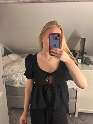 Svart blus med knyt och puffärm - Säljer denna svarta blus med puffiga korta ärmar och två knyt framtill, den är från Gina Tricot i storlek xs