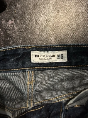 Mörkblå jeans från Pull&Bear - Säljer ett par mörkblå jeans från Pull&Bear i klassisk modell med raka ben och fem fickor. Jeansen har normal passform och är tillverkade i jeansmaterial med snygga kontrastsömmar. Perfekta för en chill och stilren look.