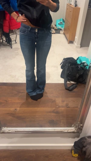 Blå bootcut jeans - Säljer ett par blå bootcut jeans med låg midja och snygg detalj på bakfickorna. Jeansen har klassisk femficksdesign och är gjorda i mjukt denimtyg som sitter skönt. Perfekt för dig som gillar en retro vibe och vill sticka ut lite extra.