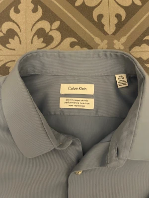 Ljusblå skjorta från Calvin Klein - Snygg ljusblå skjorta från Calvin Klein i slim fit-modell. Skjortan har klassisk krage, långa ärmar och knappar framtill. Tillverkad i bomull och polyester för en mjuk och lättskött känsla. Perfekt för dig som gillar stilrena och enkla plagg. Skjortan är storlek L. Retailpris på denna ligger på ungefär 800-1100 kronor. Endast använd vid ett tillfälle så skicket är 10/10. Tveka inte en sekund på att höra av dig vid funderingar😄. / Isak 