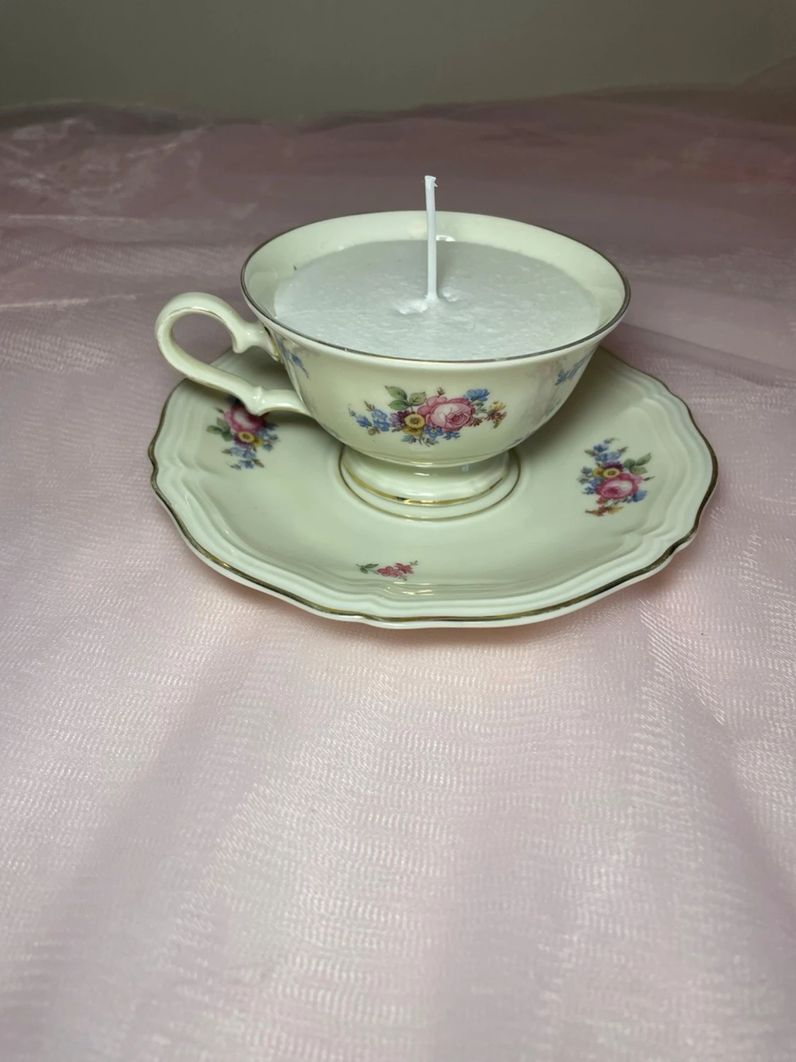 Doftljus i en tekopp med en vit kräm färgad flerfägsblommig design, nr 1