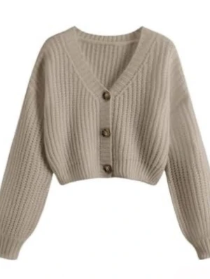 Beige croppad stickad kofta - Säljer en beige croppad stickad kofta med v-ringning och stora knappar framtill. Koftan har långärmad passform och ribbad struktur som ger en mysig och trendig look. Perfekt att slänga över en topp för extra stilpoäng.