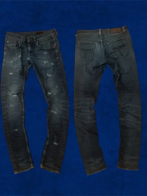 Customized Tiger of sweden jeans - Säljer ett par mörkblå skinny jeans med slitningar och tvättade detaljer. Jeansen har klassisk femficksdesign och smal passform som sitter tajt längs benen. Perfekta för dig som gillar en trendig och avslappnad look.