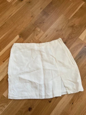 Vit linnekjol med slits - Jättefin vit kjol från H&M i linneblandning. Kjolen har en enkel design med en liten slits framtill som ger en snygg touch. 