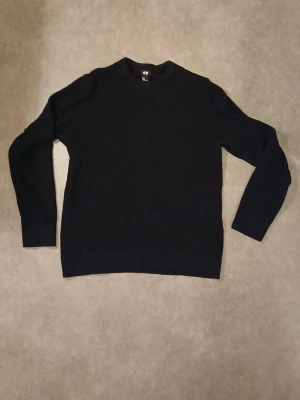 Svart stickad tröja från H&M L - En svart stickad tröja från H&M i storlek L. Tröjan har rund halsringning och långa ärmar. Materialet är en mix av bomull och syntet vilket gör den både mjuk och bekväm. Perfekt för lager-på-lager under kyliga dagar. Känns mer som en medium. 
