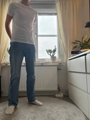 ljusblå jeans straight fit - Säljer ett par klassiska Levi's 501 jeans i ljusblå tvätt med rak passform. Jeansen har fem fickor, knappgylf och är tillverkade i slitstark bomull. Perfekt för dig som gillar en tidlös och chill stil. Passar dig som vill ha jeans med normal passning och straight legs.