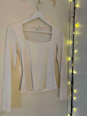 Vit långärmad topp från H&M - Säljer en enkel och stilren vit långärmad topp från H&M i storlek XS. Toppen har en fyrkantig urringning och är gjord i mjuk bomullsmix😍