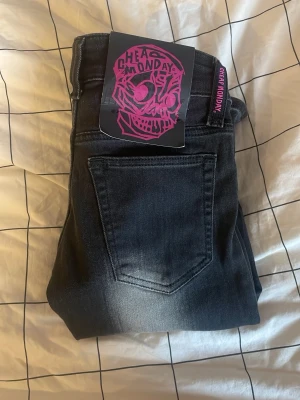 Cheap Monday svarta bootcut jeans - Säljer ett par svarta bootcut jeans från Cheap Monday med cool faded effekt längs benen. Klassisk femficksmodell med knapp och dragkedja. Jeansen har en tydlig Cheap Monday-logga i rosa på bakfickan och är tillverkade i jeansmaterial. Dom är cirka 30cm rakt över,strl 24/32. Helt nya