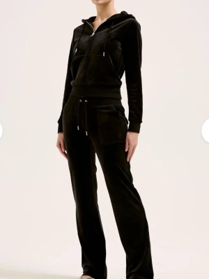 Svarta juicycouture byxor  - Säljer ett par svarta juicycouture byxor i mjuk sammet med raka ben och dragsko i midjan. Byxorna har stora fickor fram och bakfickor med knappdetaljer. Perfekta för en chill och avslappnad stil.