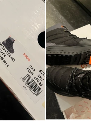 Nya oanvända Svarta vinterboots från Swims - Nya i kartong nypris 2500kr. Snow Mid Runner. Säljer ett par svarta boots från Swims med snörning och orange detaljer vid öglorna. Skorna har en robust platt sula och quiltad ovandel i syntetmaterial, perfekt för kalla dagar. Märkeslogga på plösen och dragflik baktill för enkel påtagning. Normal i storlek Unisex-modell Vattentät ripstop-nylon Värmeisolerad  Snow Runner – tillverkad för både män och kvinnor – passar när din dagliga rutin kräver att du släpar dig igenom snöblandat regn, snöblandat