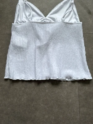 Vit omlottopp från Amisu XS - Säljer en vit omlottopp från Amisu i storlek XS. Toppen har tunna axelband, v-ringning och knyt framtill. Tröjan är helt öppen framtill. Materialet är lätt och har en krinklad struktur. Perfekt till sommaren och enkel att styla med jeans eller kjol. Tröjan har aldrig använts.
