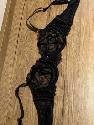 Svart spets-bh från Lounge - Svart balcony bh från Lounge i modellen Yasmine. Bh:n har transparent spets med blommigt mönster, dekorativa band och en snygg v-ringad form. Materialet är en mix av polyester, polyamid och elastan. Nypris ca 600kr. Endast provad.