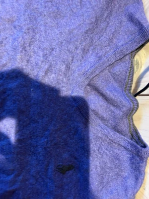 Lila stickad tröja från Ralph Lauren - Säljer en lila stickad tröja från Ralph Lauren med klassisk broderad logga på bröstet. Tröjan har rund halsringning, ribbade muddar och är långärmad. Perfekt för dig som vill ha en stilren och bekväm look. Saknar dock en tag