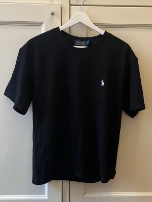Svart t-shirt från Polo Ralph Lauren - Svart Ralph lauren tshirt med en vit logga. Aldrig använd. Str S i herr