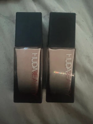Huda Beauty Foundation Milk Shake 100B - Säljer två flaskor Huda Beauty Faux Filter Foundation i nyansen Milk Shake 100B. Det är en high coverage cream foundation i ljus beige ton. Flaskorna är fyrkantiga i glas med svart lock och rymmer 35 ml vardera. Perfekt för dig som vill ha en flawless bas. Man får båda för 500 dom är helt nya 