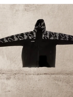 Svart vindjacka Corteiz Litework - Säljer en svart vindjacka från Corteiz Litework med grått graffiti-mönster på huva och ärmar. Jackan har dragkedja framtill, fickor med dragkedja och justerbar huva. Materialet är syntet och jackan har en clean streetwear-vibe.