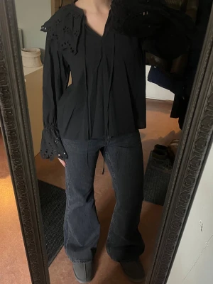 Svart blus från Stockholm MQ med spets och peterpankrage - En svart blus från Stockholm MQ med spets och peterpan krage. Lite oversized, storlek s. Knytband i halsen. Spets kring kragen och längs ärmarna 