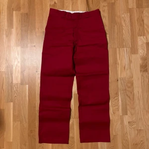 Röda Dickies 874 byxor - Säljer ett par klassiska Dickies 874 Original Fit i rött. Byxorna har raka ben, bälteshällor och två bakfickor. Materialet är slitstark polyesterblandning som ger en clean och stilren look. Perfekta för dig som vill ha en streetwear vibe.