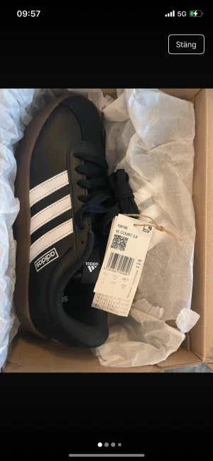 Adidas VL Court 3.0 svarta sneakers - Svarta Adidas VL Court 3.0 sneakers med klassiska vita ränder på sidorna och brun sula. Skorna har snörning och är gjorda i syntetmaterial med en platt sula och rund tå. Perfekta för dig som gillar en clean och sportig stil.