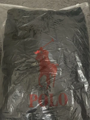 Svart pufferjacka från Polo Ralph Lauren - Säljer en svart pufferjacka från Polo Ralph Lauren med huva och flera dragkedjeförsedda fickor. Jackan har det klassiska röda Polo-logot broderat på bröstet och är perfekt för kalla dagar. Stängs med dragkedja och har en clean, sportig look.