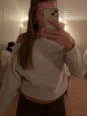 Ljusgrå offshoulder stickad tröja - Säljer en ljusgrå stickad tröja med offshoulder-design. Tröjan har en loose passform och långa ärmar, perfekt för mysiga dagar. Enkel och stilren modell som är lätt att matcha med olika outfits.